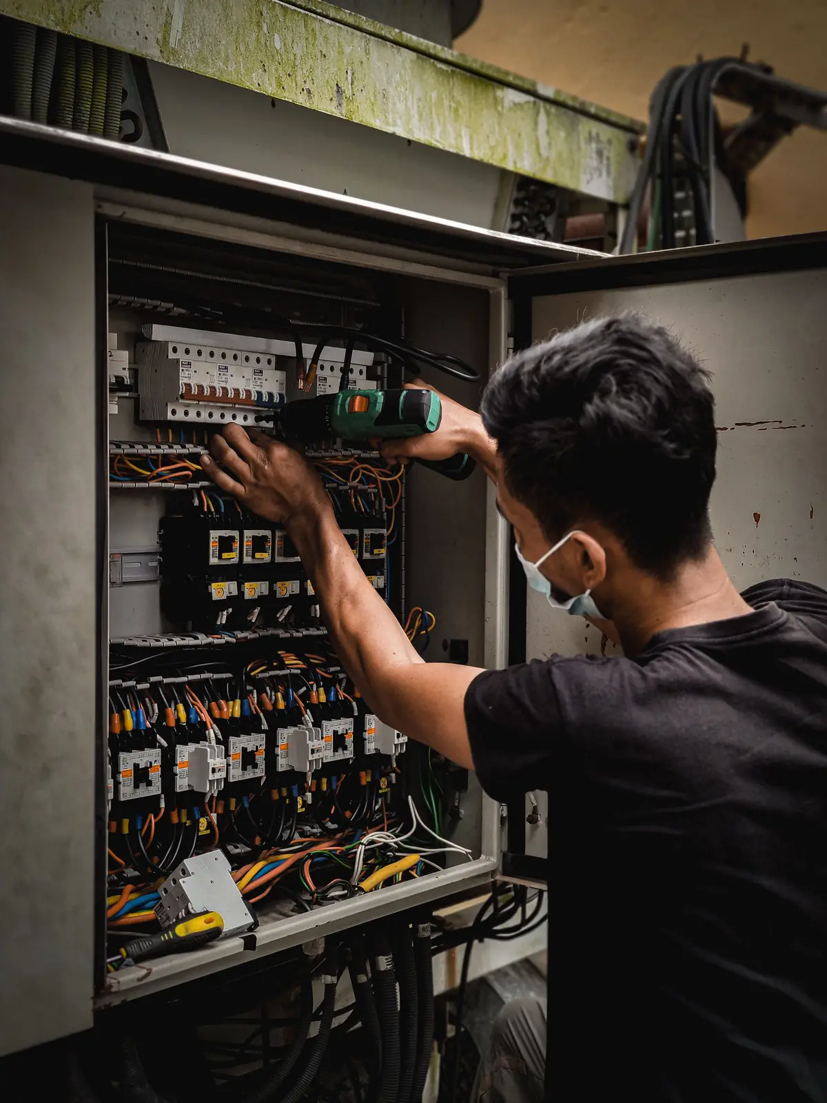 An electrician working inside a large distribution board, for outlet repair in Oklahoma City