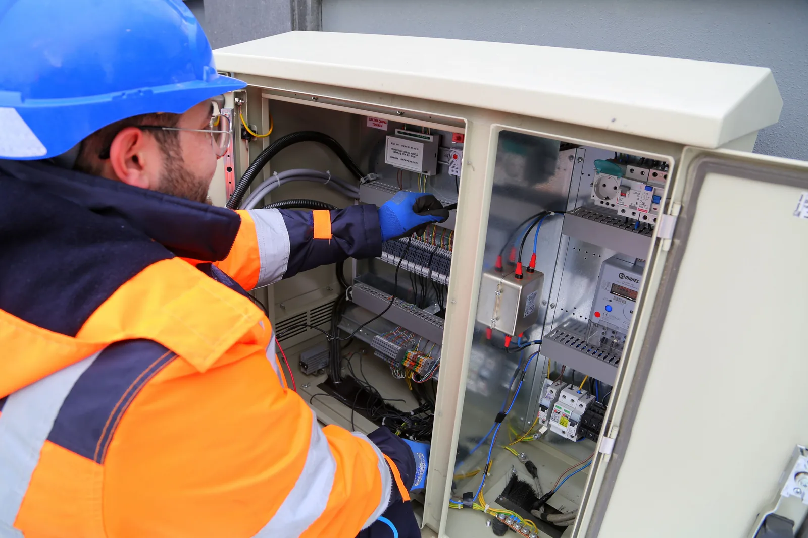 An electrician working in an outdoor service cabinet, for surge protection in Oklahoma City